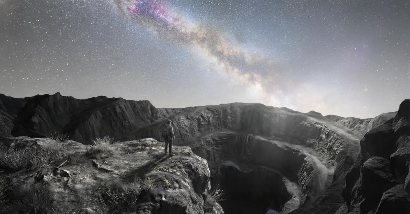 Explorer surveying vast canyon beneath the Milky Way